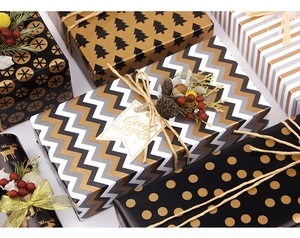 Close-up of premium gold and black Christmas wrapping paper with festive patterns and pine cones