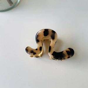 Elegant wave-shaped hair claw clip in tortoiseshell acrylic with golden hinge details