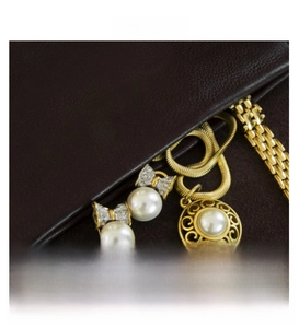 Detailed view of pearl earrings with bow accents and pendant on leather texture