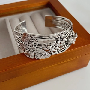 Close-up of vintage silver cuff bracelet featuring carved butterfly and flower details