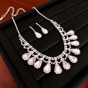 Macro view of silver geometric necklace and teardrop earrings with sparkling rhinestones