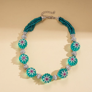 Detail of vintage necklace with green resin flower beads and purple crystal center