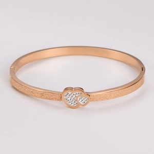 Detail of rose gold stainless steel bracelet with frosted finish and heart charm