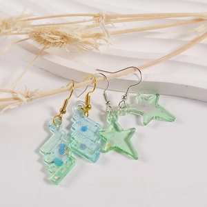 Glittering star and lightning resin earrings hanging on dry branches with a white tray