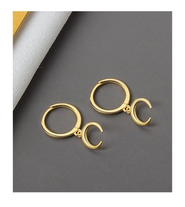 Detail showing elegant gold crescent moon hoop earrings on a minimalist grey surface