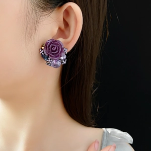 Detailed view of luxury purple rose floral earrings featuring crystals on a fashion model