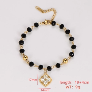Macro shot of gold-plated chain bracelet with black faceted beads and flower pendant