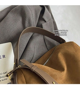 Close-up of brown suede pillow bag featuring sturdy handles and gold metal hardware