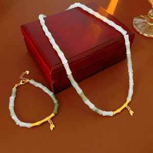 Detail view of bamboo leaf jewelry set with white and green beads on a wooden box