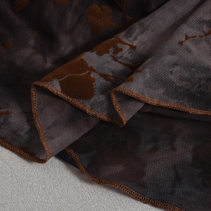Close-up of brown mesh fabric featuring flocked floral patterns and delicate stitching