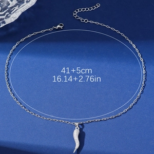 Silver horn pendant necklace with sparkling rhinestones on textured blue fabric background