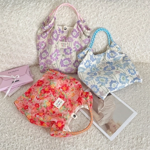 Detailed view of floral tote bags in purple, blue and orange with woven handles