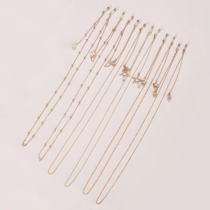 Gold metal eyewear chains with pearl and star pendants on beige background