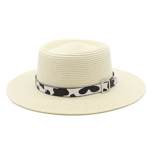 Detail of flat top straw hat with cow print band and silver metal buckle decoration