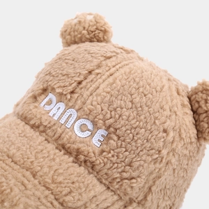 Detailed close-up of fluffy Sherpa texture and white 'DANCE' embroidery on brown bear ear cap
