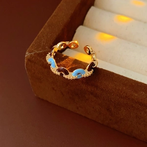 Dettaglio dell'anello regolabile dorato con smalto colorato e zirconi brillanti incastonati