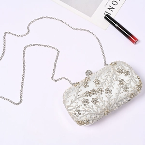 Detailed close-up of a white bridal clutch featuring floral pearl and rhinestone embellishments