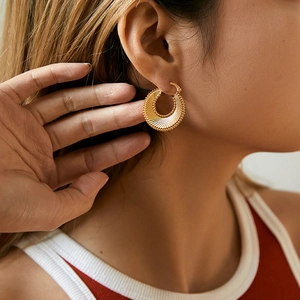 Detailed close-up of vintage gold spiral hoop earrings with radiant texture on ear