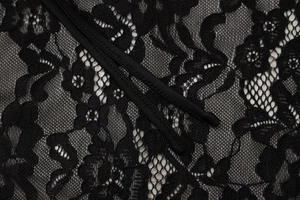 Detail of delicate floral lace embroidery and sheer mesh texture on a black summer dress
