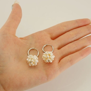 Détail de boucles d'oreilles créoles en acier inoxydable avec grappes de perles blanches