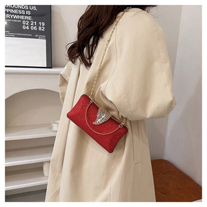 Elegant red glitter evening clutch with golden leaf clasp and chain strap detail