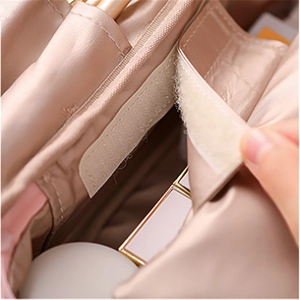 Détail de la trousse de maquillage en satin champagne avec fermeture velcro et poches