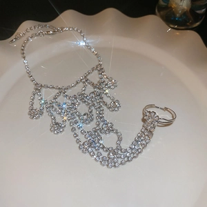 Macro detail of silver rhinestone ring bracelet connector on a white wavy ceramic plate