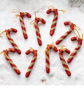 Detail of nine red and gold glitter candy cane ornaments arranged on a white snowy surface