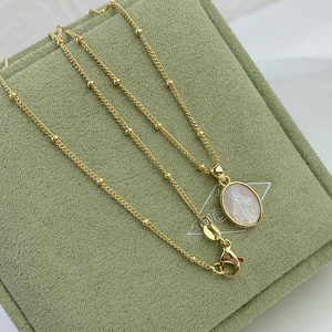 Macro detail of gold Virgin Mary necklace with oval mother of pearl shell pendant