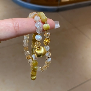 Détail de bracelets en perles d'oeil de tigre avec un pendentif nuage doré poli