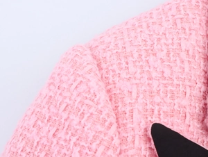 Nahaufnahme der hochwertigen rosa Tweed-Stoffstruktur und der Webmuster an der Schulter