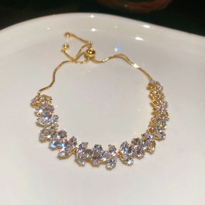 Macro view of golden adjustable bracelet with marquise-cut zircons on a white tray