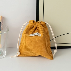 Close-up of yellow corduroy storage bag with cream cotton drawstring and brand label