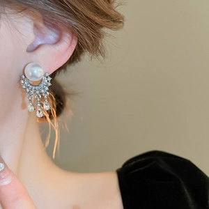 Detail of silver drop earrings with white pearls, pavé crystals and fringe tassels