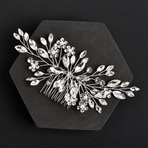 Macro detail of bridal hair comb with silver wires, crystals, and white pearls on black base