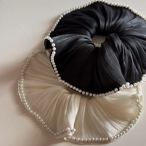 Detail of beige and black satin scrunchies with white pearl edges in a set of two