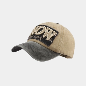 Detail der Vintage-Baseballkappe mit NOW-Stickerei und abgenutzter Schirmkante