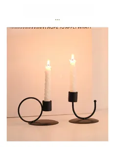 Gros plan de bougeoirs en métal noir en U avec bougies en spirale allumées