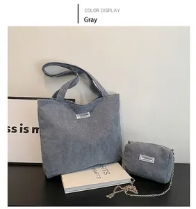 Detail of grey corduroy tote bag set with fashion label and gold chain strap