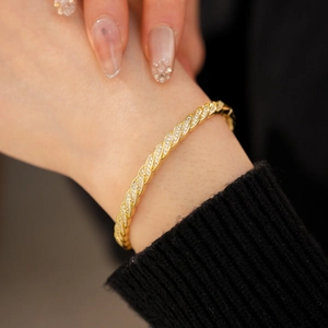 Detailed close-up of a gold twisted cuff bracelet featuring pavé set sparkling zircon stones