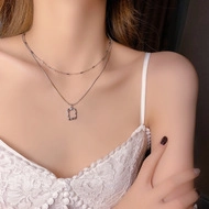 Detail view of double-layer silver necklace with geometric square pendant on neck