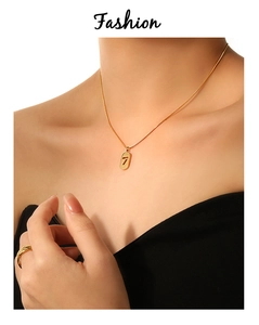 Detailed shot of golden snake chain with oval lucky number 7 pendant on skin