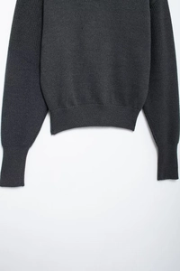 Detailed macro view of dark grey knit texture and ribbed hem on a casual hoodie sweater