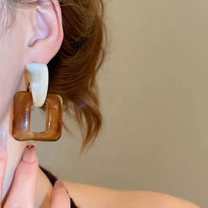 Detail of amber resin drop earring with white hook on model for a vintage aesthetic