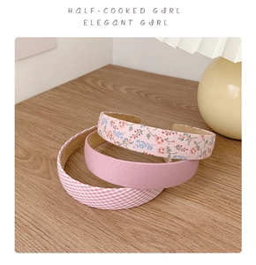 Close-up of three retro floral and plaid headbands on a rustic wooden table surface