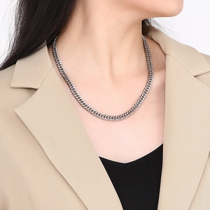 Close-up of silver Cuban link chain necklace worn with a beige blazer for a hip-hop style