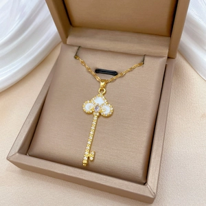 Elegant gold key necklace with white shell inlay and crystals in a jewelry box
