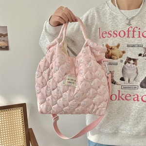 Detail of pink quilted cotton bag featuring cartoon rabbit prints and a woven logo label
