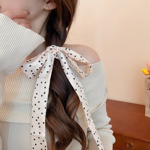 Close-up of a vintage beige polka dot satin hair scarf tied on a braided hairstyle