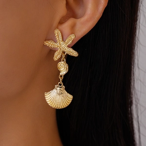 Close-up of golden starfish and seashell drop earrings featuring textured metallic finish